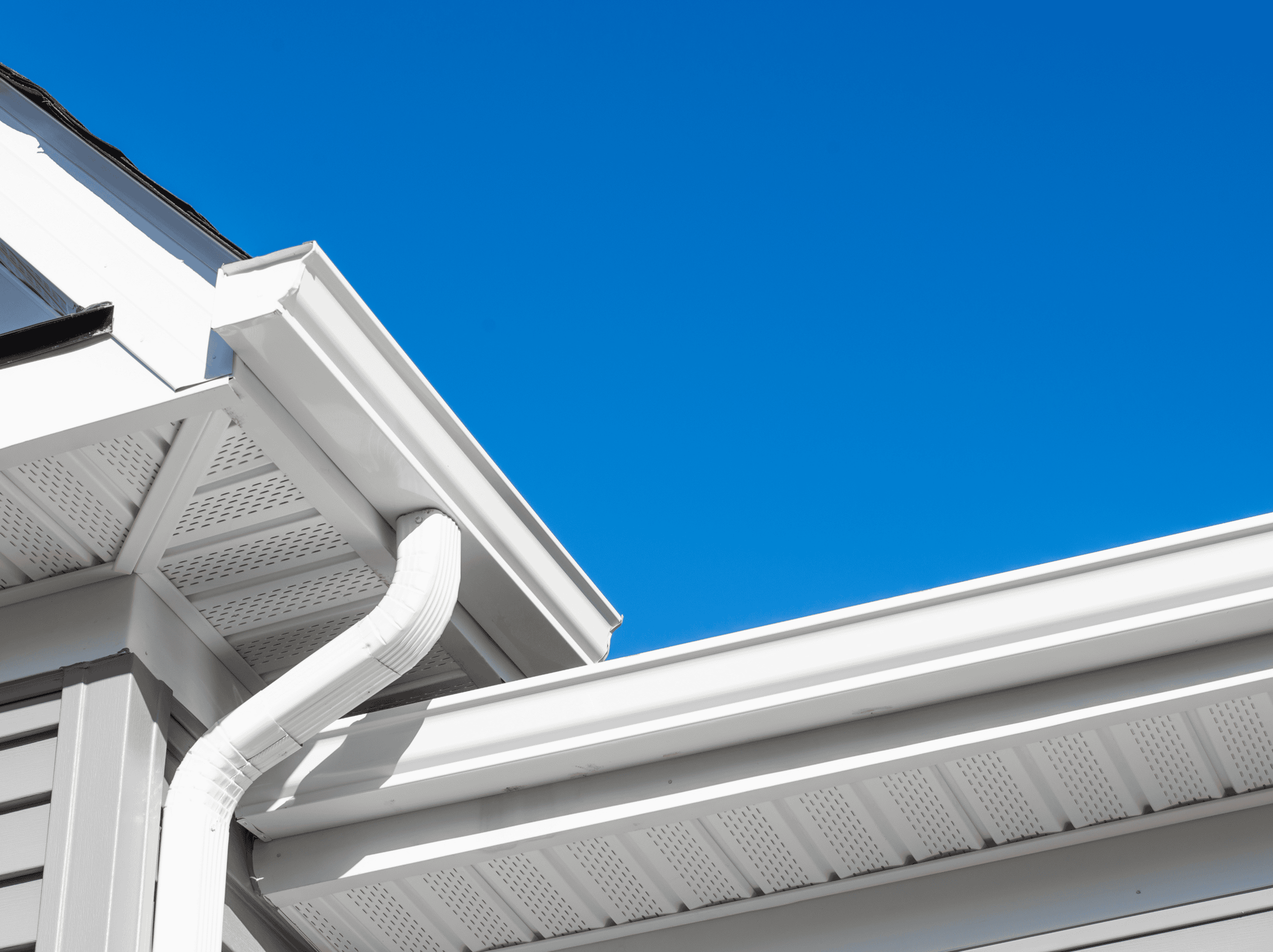 Professional gutter installation on residential home with white gutters and downspouts.